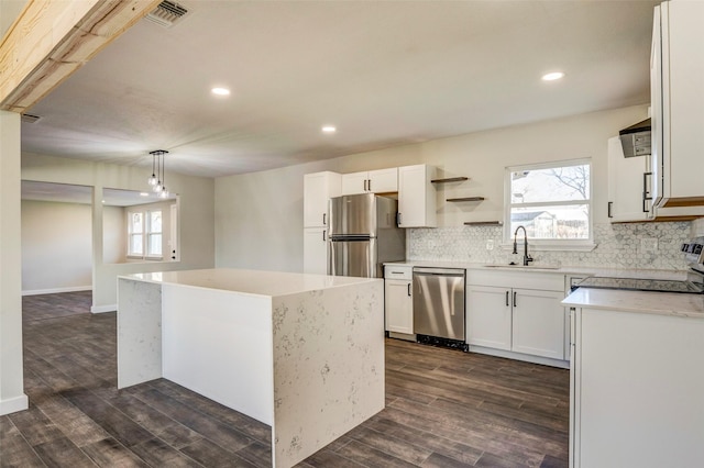 kitchen featuring a center island, hanging light fixtures, white cabinets, appliances with stainless steel finishes, and sink