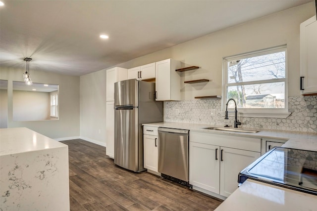 kitchen with decorative light fixtures, stainless steel appliances, white cabinetry, and sink