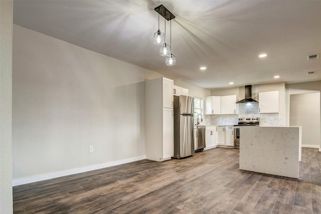 kitchen with decorative light fixtures, wall chimney range hood, white cabinetry, appliances with stainless steel finishes, and wood-type flooring