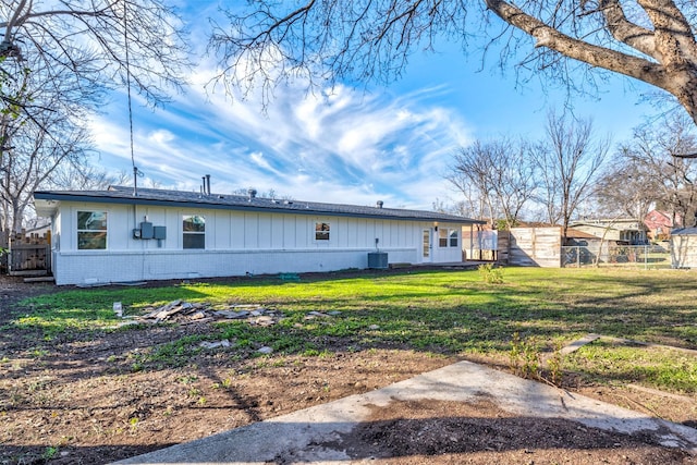 rear view of property featuring central air condition unit and a lawn