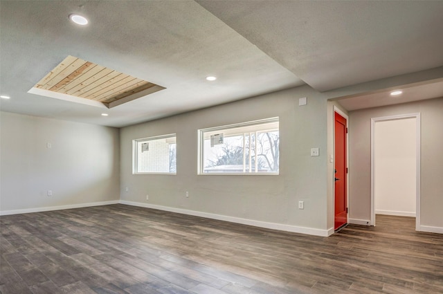 spare room with a textured ceiling, a skylight, and dark hardwood / wood-style flooring