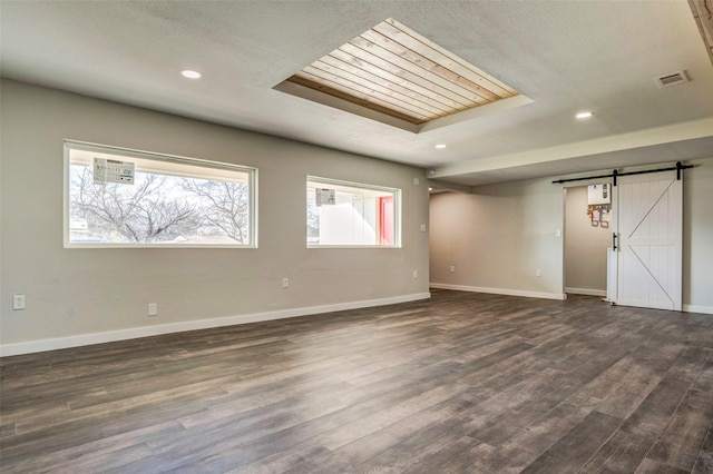 empty room featuring a barn door and dark hardwood / wood-style flooring