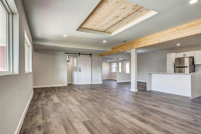 unfurnished living room featuring a barn door and wood-type flooring