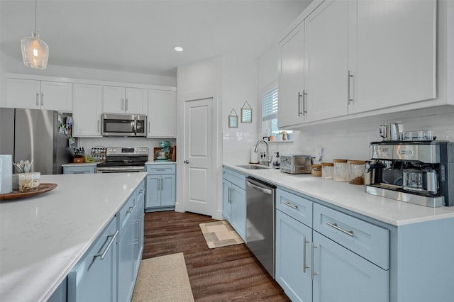 kitchen featuring appliances with stainless steel finishes, sink, white cabinets, hanging light fixtures, and dark wood-type flooring