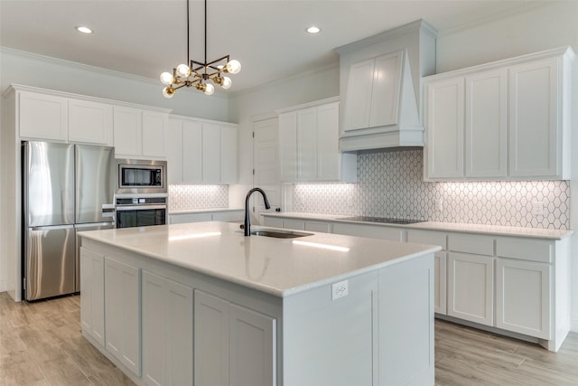 kitchen with stainless steel appliances, backsplash, premium range hood, a chandelier, and a kitchen island with sink