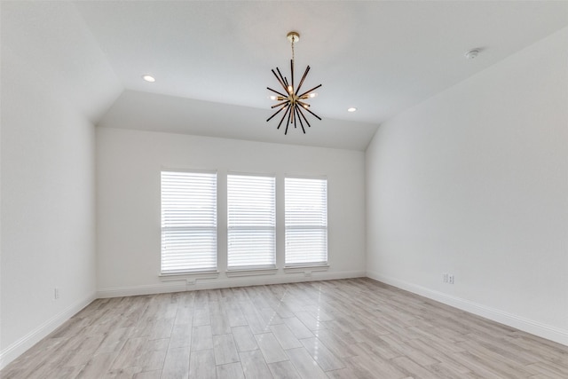 empty room featuring light hardwood / wood-style flooring, lofted ceiling, and a chandelier