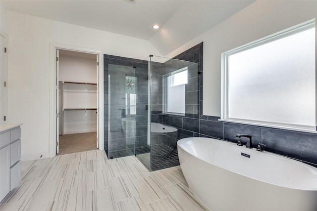 bathroom featuring lofted ceiling, shower with separate bathtub, and vanity