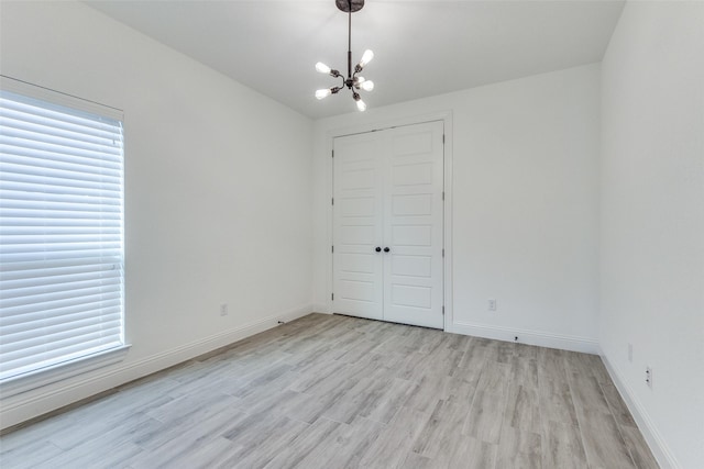 unfurnished bedroom featuring a closet, an inviting chandelier, and light hardwood / wood-style floors