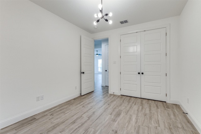 unfurnished bedroom with light hardwood / wood-style flooring, a closet, and a chandelier