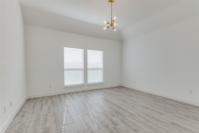 empty room featuring a notable chandelier, vaulted ceiling, and light hardwood / wood-style flooring