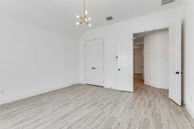 unfurnished bedroom featuring light wood-type flooring, an inviting chandelier, and lofted ceiling