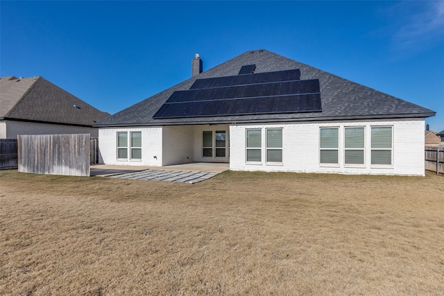 back of house featuring a patio, a yard, and solar panels