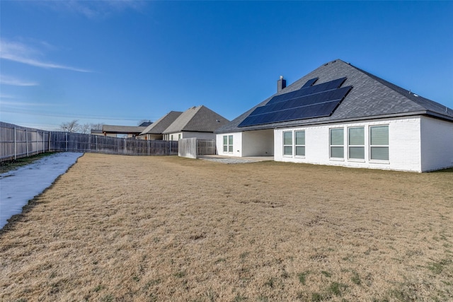 back of property featuring solar panels and a yard