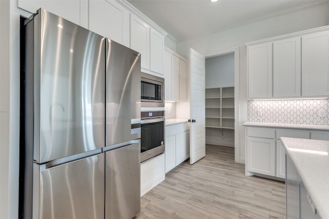 kitchen featuring white cabinets, appliances with stainless steel finishes, light hardwood / wood-style flooring, and tasteful backsplash