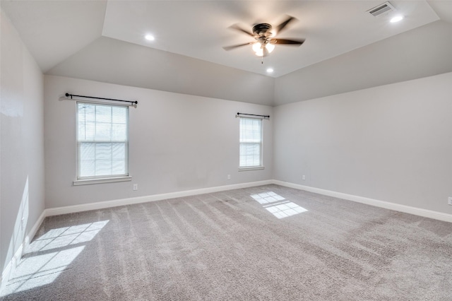 empty room featuring ceiling fan, vaulted ceiling, and light colored carpet