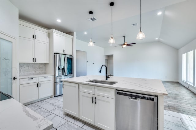 kitchen with stainless steel appliances, a center island with sink, decorative backsplash, white cabinetry, and sink