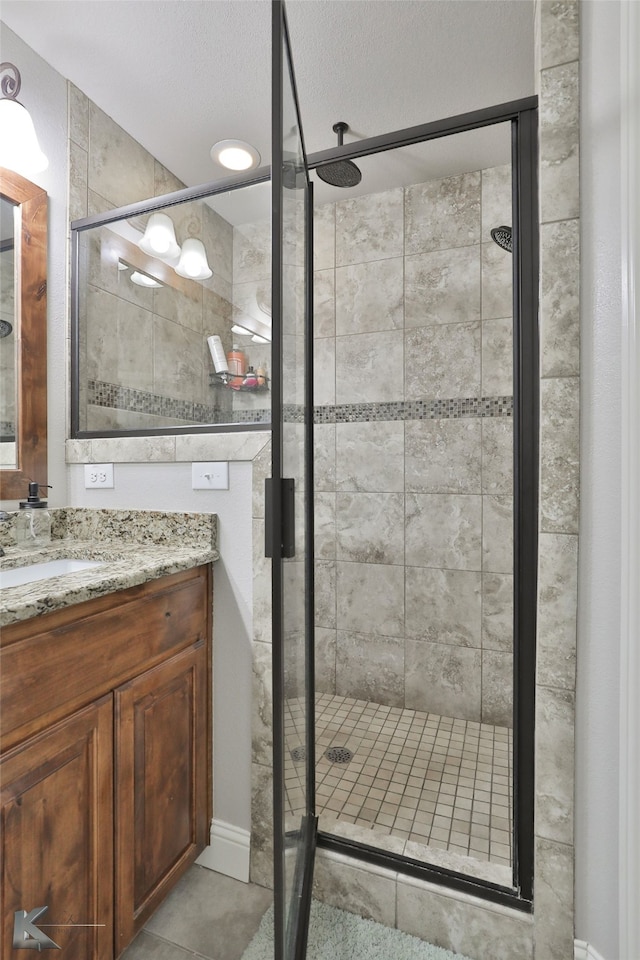 bathroom with a shower with shower door, vanity, a textured ceiling, and tile patterned floors