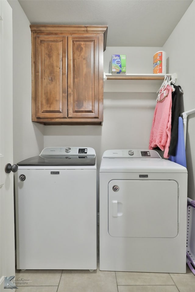 laundry area with independent washer and dryer, light tile patterned floors, and cabinets