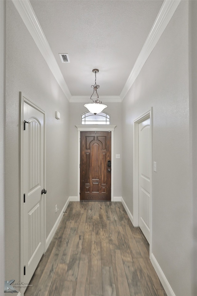 doorway with a textured ceiling, dark hardwood / wood-style flooring, and ornamental molding