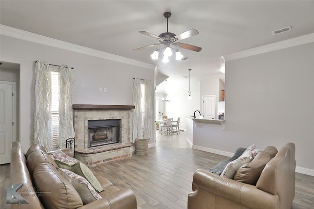 living room with ceiling fan, ornamental molding, a stone fireplace, and wood-type flooring