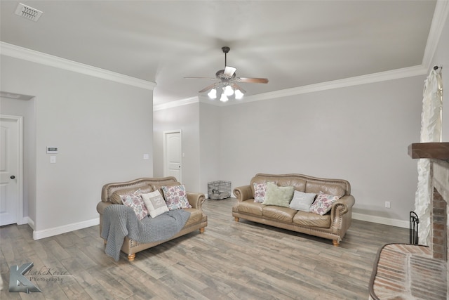 living room featuring a brick fireplace, hardwood / wood-style flooring, ceiling fan, and ornamental molding