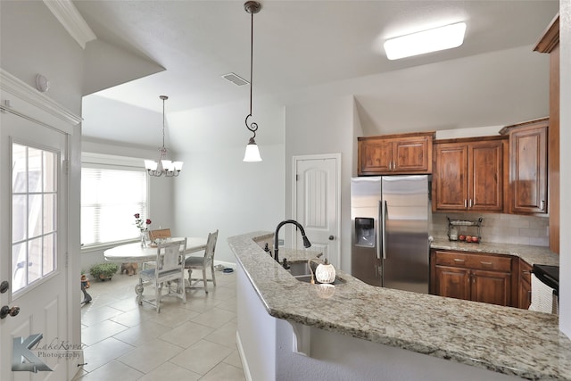 kitchen featuring light stone countertops, stainless steel fridge, sink, tasteful backsplash, and pendant lighting