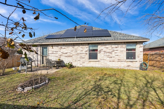 back of house with solar panels, a patio, and a lawn