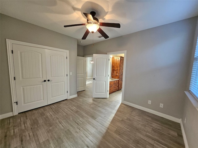 unfurnished bedroom with ceiling fan, a closet, ensuite bathroom, and light hardwood / wood-style floors