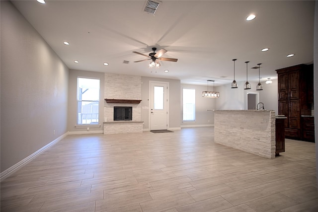 unfurnished living room with ceiling fan and a stone fireplace