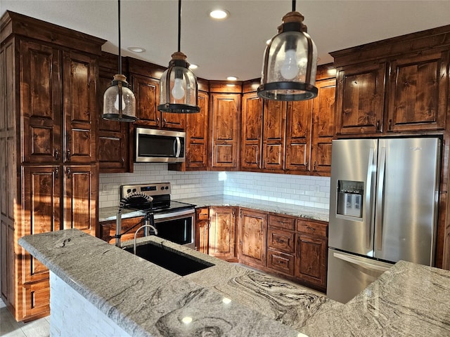 kitchen with appliances with stainless steel finishes, decorative light fixtures, tasteful backsplash, sink, and light stone counters