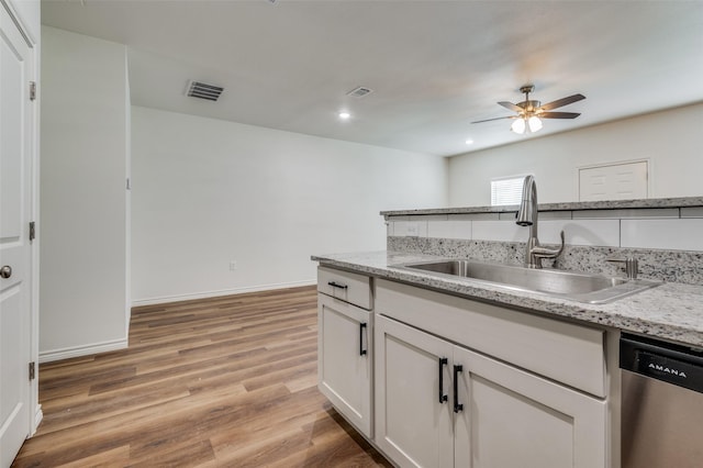 kitchen featuring white cabinetry, sink, stainless steel dishwasher, light stone countertops, and light hardwood / wood-style flooring