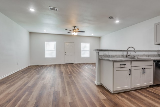 kitchen with wood-type flooring, sink, stainless steel dishwasher, ceiling fan, and light stone countertops