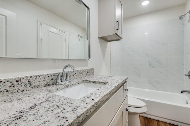 full bathroom with vanity, tiled shower / bath, hardwood / wood-style flooring, and toilet