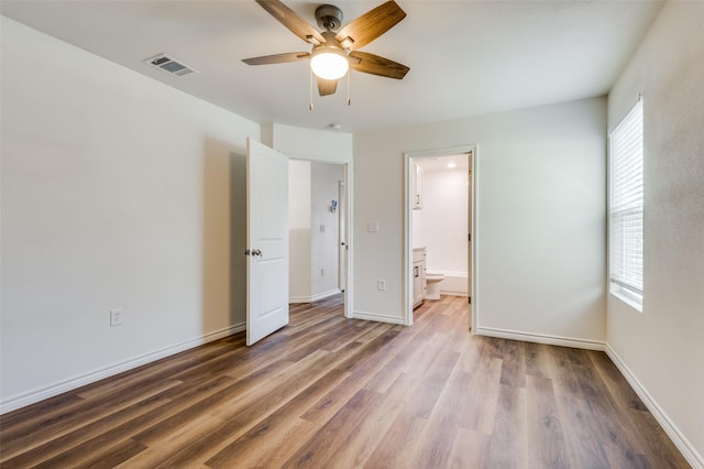 unfurnished bedroom featuring ensuite bath, dark hardwood / wood-style floors, and ceiling fan