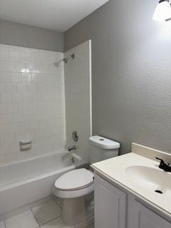 full bathroom featuring toilet, vanity, tile patterned floors, and tiled shower / bath combo