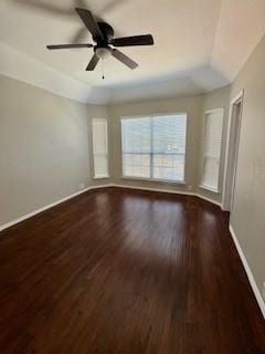 empty room with dark hardwood / wood-style flooring, ceiling fan, and vaulted ceiling