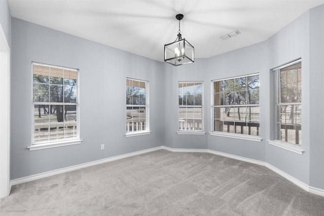 spare room with light carpet, a wealth of natural light, and a notable chandelier