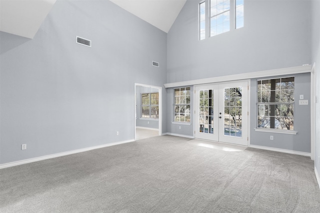 unfurnished living room with high vaulted ceiling, french doors, and carpet flooring