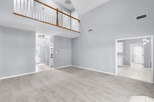 unfurnished living room featuring light carpet and a towering ceiling