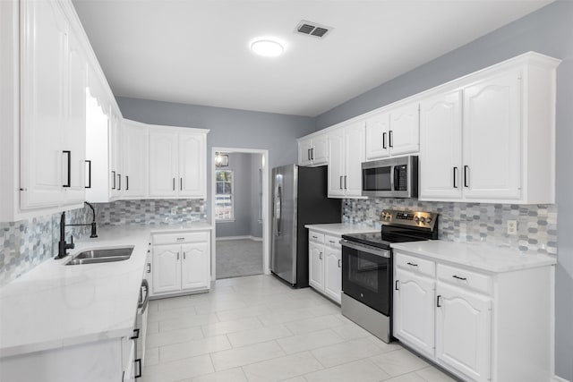 kitchen featuring stainless steel appliances, light stone counters, sink, white cabinetry, and light tile patterned flooring