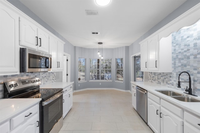 kitchen featuring stainless steel appliances, pendant lighting, sink, white cabinetry, and tasteful backsplash