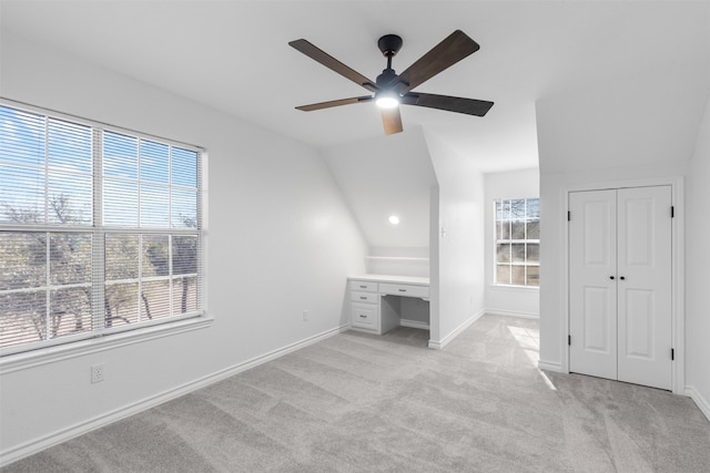 unfurnished bedroom featuring ceiling fan, vaulted ceiling, and light colored carpet