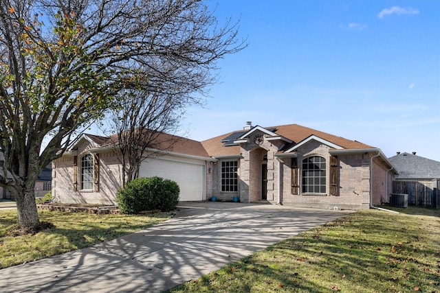 ranch-style house featuring a front lawn, a garage, central air condition unit, and solar panels