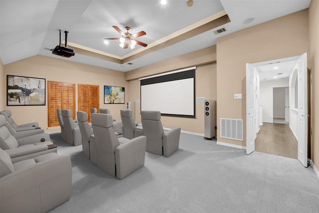 carpeted home theater with ceiling fan, a tray ceiling, and crown molding