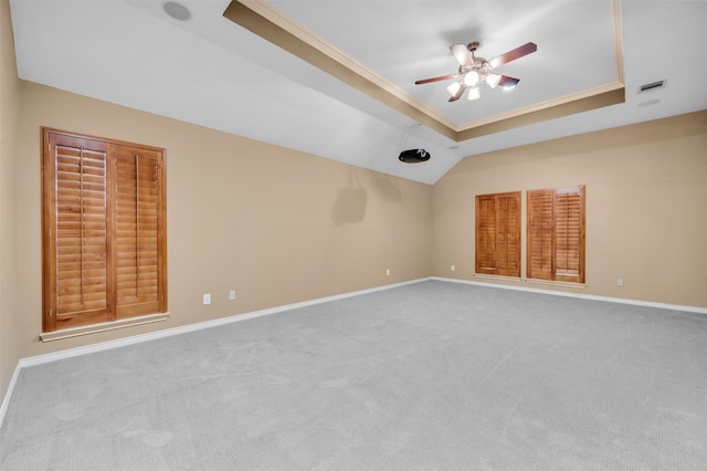 empty room with ceiling fan, light colored carpet, ornamental molding, and a raised ceiling