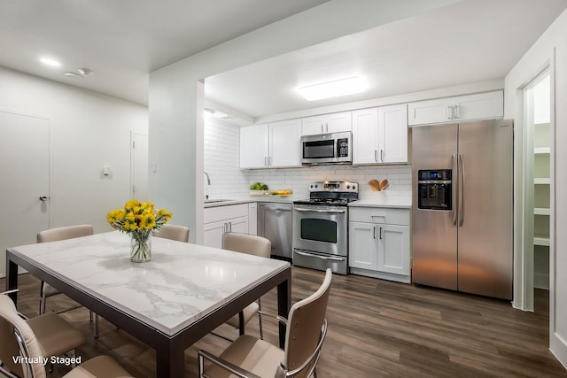 kitchen featuring dark wood-type flooring, stainless steel appliances, tasteful backsplash, white cabinetry, and sink