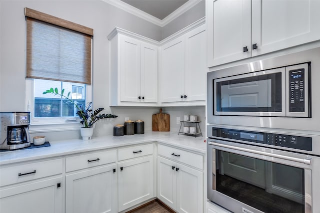 kitchen featuring light stone countertops, appliances with stainless steel finishes, ornamental molding, and white cabinetry