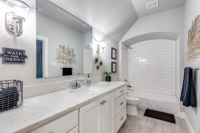 full bathroom featuring toilet, tiled shower / bath, hardwood / wood-style floors, and vanity