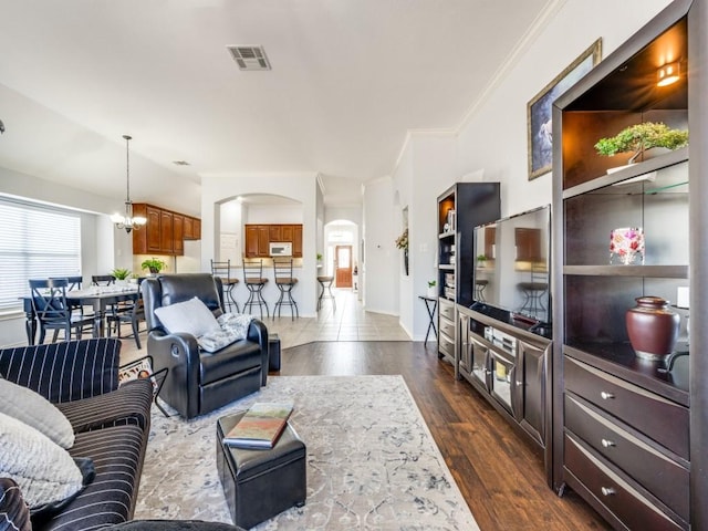 living room featuring a notable chandelier, dark wood-type flooring, and crown molding