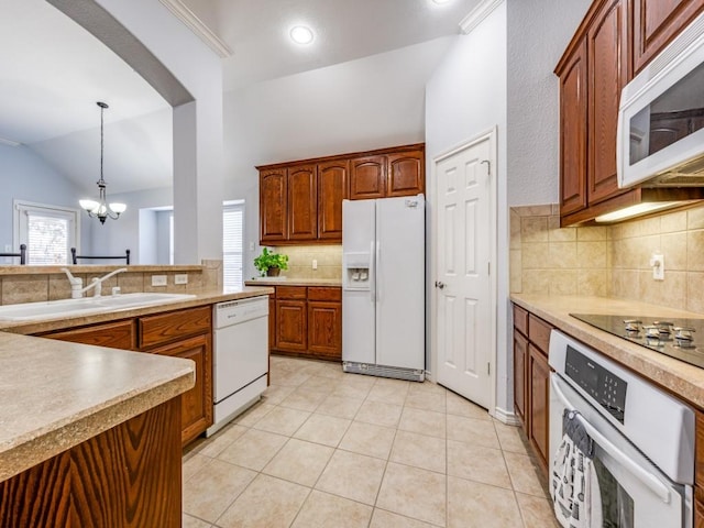 kitchen with sink, decorative light fixtures, white appliances, a healthy amount of sunlight, and a chandelier